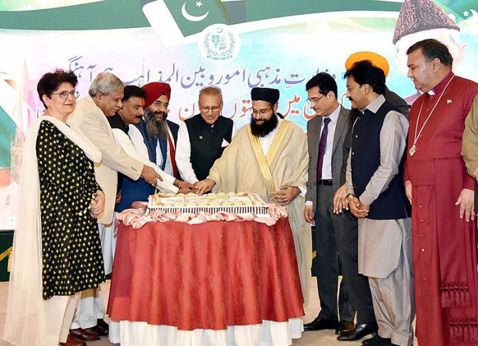 President Dr. Arif Alvi cutting cake with members of the minority communities in celebration of Minorities' Day, at Aiwan-e-Sadr