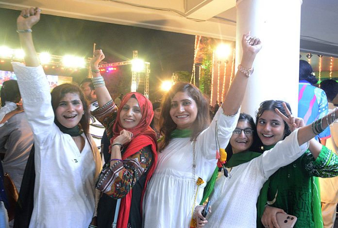 Girls dressed in green and white suits are enthusiastically celebrating at the Azadi Festival hosted at the Arts Council of Pakistan