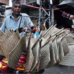 A vendor displaying the handmade hand fans on his motorcycle for customers while shuttling