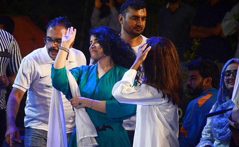 Girls dressed in green and white suits are enthusiastically celebrating at the Azadi Festival hosted at the Arts Council of Pakistan