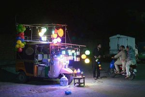 A young man selling beautiful fancy bright decorated lightning lamps on his rickshaw