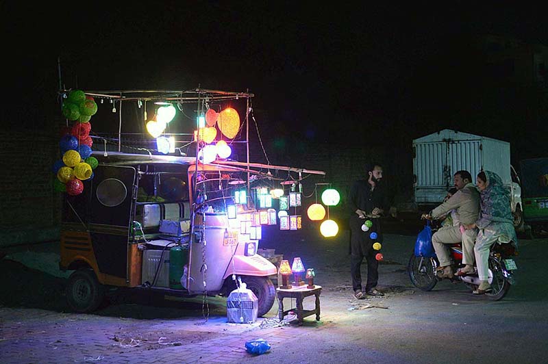 A young man selling beautiful fancy bright decorated lightning lamps on his rickshaw