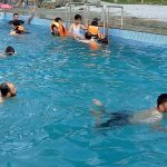 Youngsters taking bath in swimming pool to get relief from the hot weather in the city.