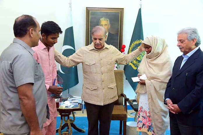 Prime Minister Muhammad Shehbaz Sharif presenting a cheque of 1 million rupees to Jamshed Ali in recognition of his exceptional performance by securing the first position in Matriculation Examination 2023 in Gujranwala Board