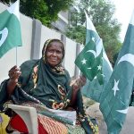 A woman displays national flags ahead of Independence Day Pakistan at her roadside stall