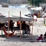 A gypsy woman busy in washes pots in front of her makeshift huts