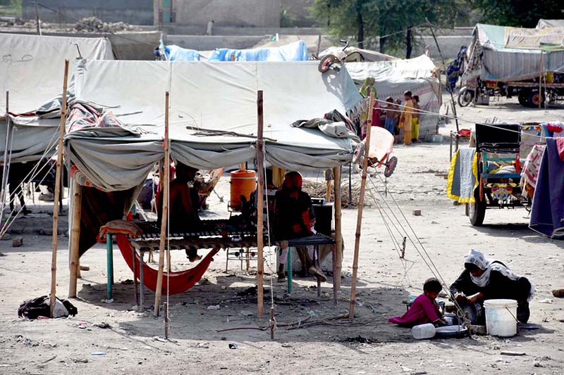 A gypsy woman busy in washes pots in front of her makeshift huts
