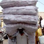 A labourer on the way while carrying heavy sacks of goods after unloading from transportation truck at Shahi Bazar