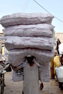 A labourer on the way while carrying heavy sacks of goods after unloading from transportation truck at Shahi Bazar