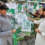Customer busy in purchasing national flag dresses for children at Qissa Khawani Bazar in preparations to celebrate Independence Day in befitting manners