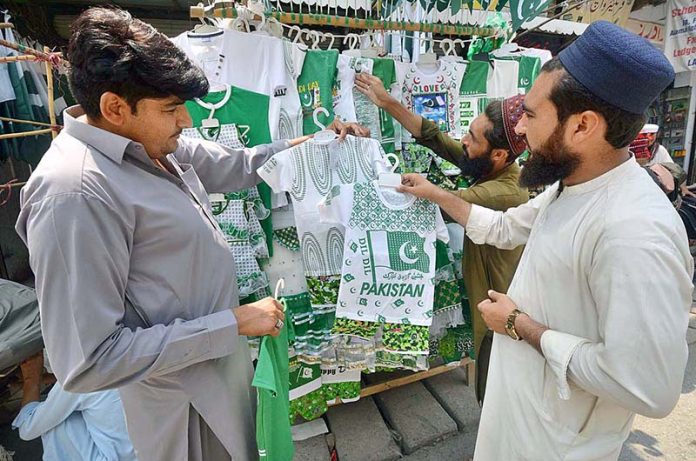 Customer busy in purchasing national flag dresses for children at Qissa Khawani Bazar in preparations to celebrate Independence Day in befitting manners