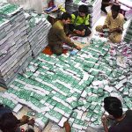 Workers tying and packing bundles of bunting Pakistani flags after printing to be used in preparations for the upcoming celebration of Independence Day across the country