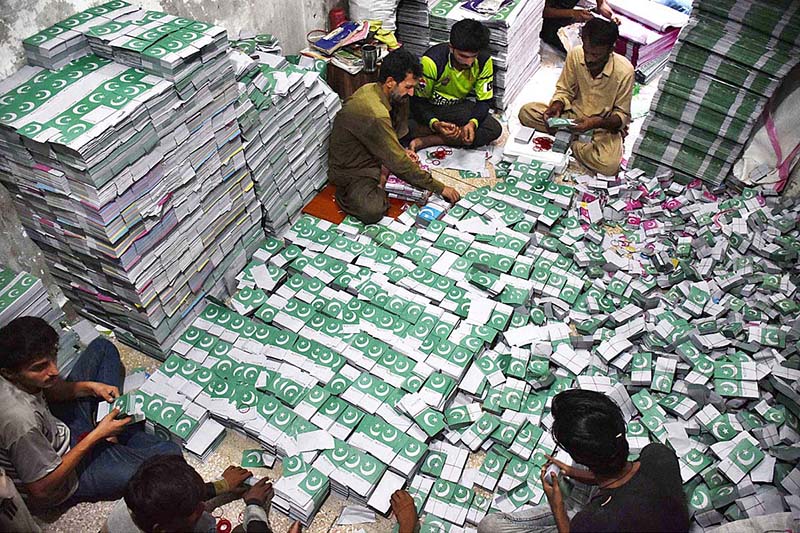 Workers tying and packing bundles of bunting Pakistani flags after printing to be used in preparations for the upcoming celebration of Independence Day across the country