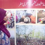 A girl looking at a picture put on display in a pictorial exhibition on 'Kashmir Exploitation Day' at Arts Council of Pakistan