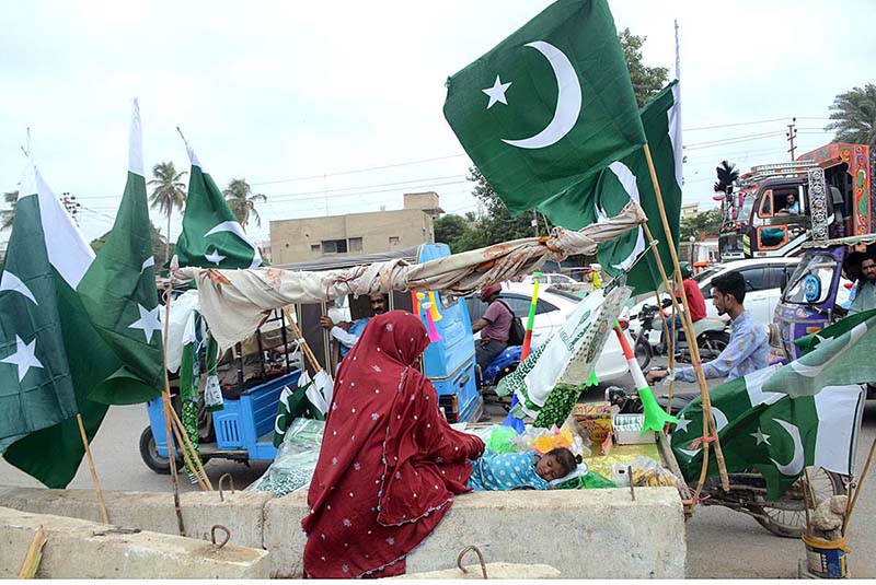 A vendor wear national flag colour face mask holds national flag for sell at his stall at paper market in connection with Pakistan's Independence Day celebrations