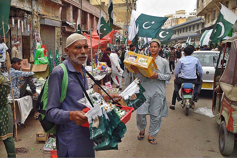 A vendor wear national flag colour face mask holds national flag for sell at his stall at paper market in connection with Pakistan's Independence Day celebrations