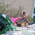 A girl is selling national flags on the roadside in preparation for Pakistan's Independence Day