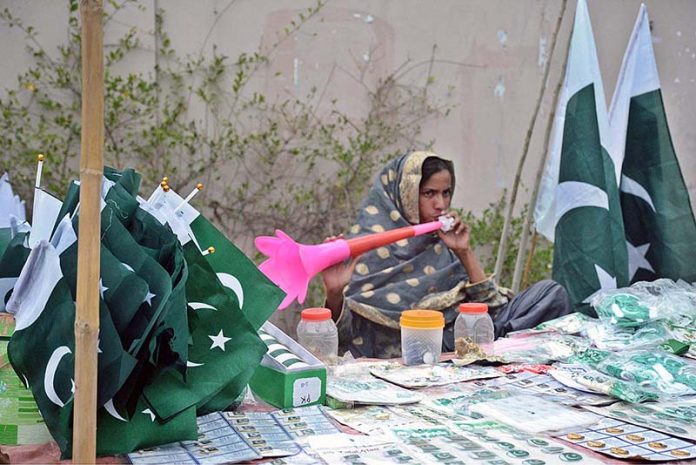 A girl is selling national flags on the roadside in preparation for Pakistan's Independence Day