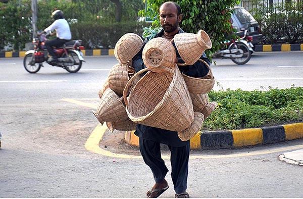 A street vendor displaying traditional handmade baskets while shuttling on the road.