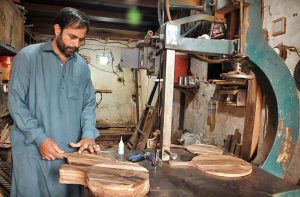 A carpenter busy in preparing wooden item at his workplace in Federal Capital.