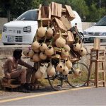 A vendor displaying bird nests and wooden stools to attract customers at his roadside setup in the Federal Capital