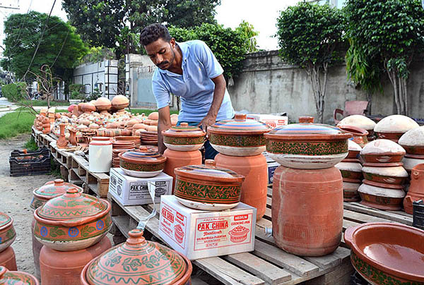 A vendor displaying clay made pots to attract customers at his roadside setup near Muslim Town market.