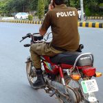 A police official on the way without wearing safety helmet and using mobile while driving motorcycle at College Road.
