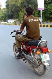  A police official on the way without wearing safety helmet and using mobile while driving motorcycle at College Road. 