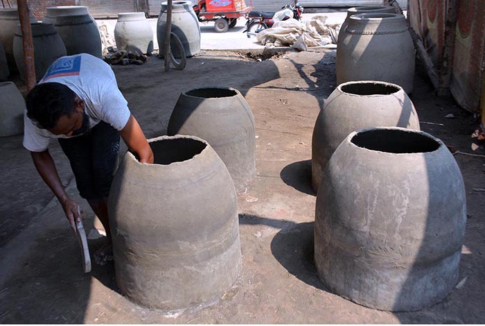 An artisan is busy in preparing a traditional oven “Tandoor” at his workplace.