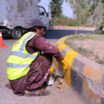 Labourer is busy colouring roadside green belt near General bus stand