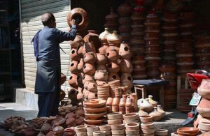 - A vendor busy in arranging and displaying clay pots to attract the customers at his roadside setup.