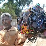 A vendor displaying Sunglasses to attract customers while shuttling on the road