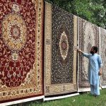 A vendor arranging and displaying carpets to attract the customers at F-10 Chowk in Federal Capital.