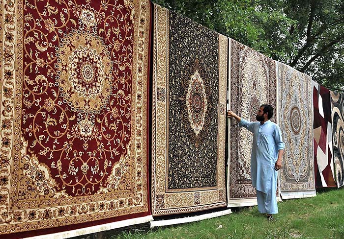 A vendor arranging and displaying carpets to attract the customers at F-10 Chowk in Federal Capital.