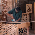 Worker is busy carving designs on the wooden sheet at his workplace
