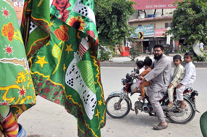 A family on motorbike saw Eid Milad-un-Nabi related stuff for selling at roadside in the Federal Capital