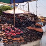 A vendor selling shoes on his roadside setup at City road