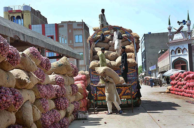 Labourers busy in unloading sacks of onion from delivery truck at Vegetable Market.