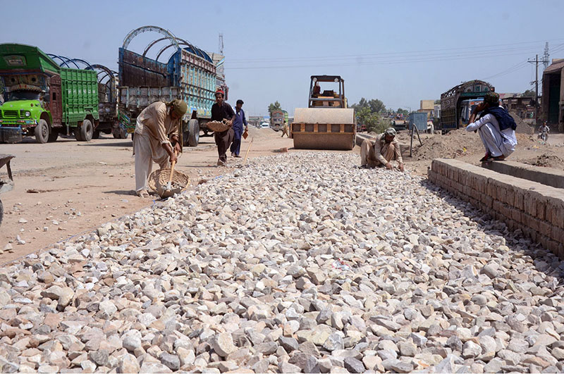 Laborers spreading stones on the road during the construction work of Muzaffargarh road