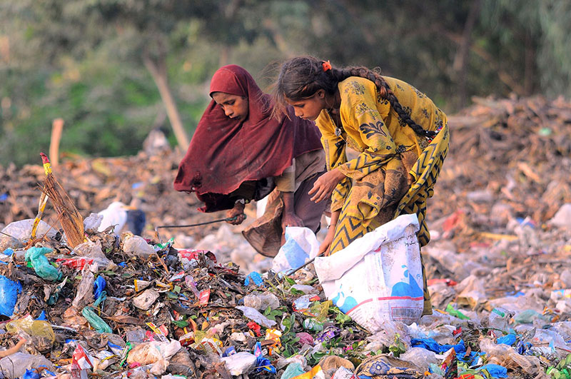 Gypsy girls searching valuables from the heap of garbage