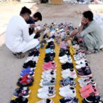 People are selecting and purchasing second hand shoes from a vendor at Zia Masjid as the mercury drops rapidly in the city