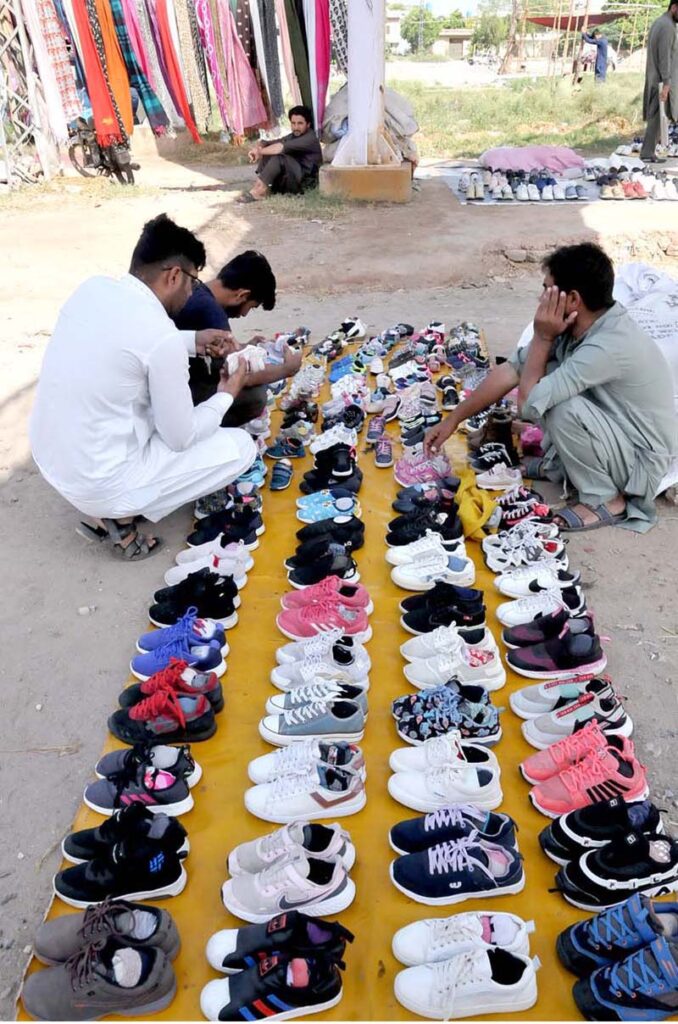 People are selecting and purchasing second hand shoes from a vendor at Zia Masjid as the mercury drops rapidly in the city