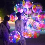 A street boy vendor displaying the colorful lighting balloons to attract the customers