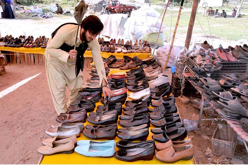 People are selecting and purchasing second hand shoes from a vendor at Zia Masjid as the mercury drops rapidly in the city