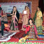 Female students performing tableau on stage at Shah Latif Girls College