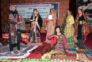 Female students performing tableau on stage at Shah Latif Girls College