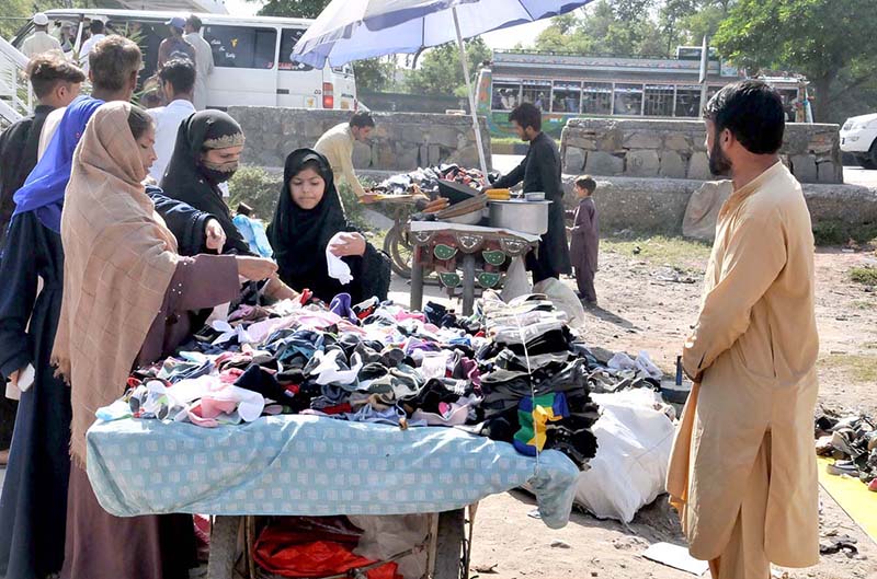 People are selecting and purchasing second hand shoes from a vendor at Zia Masjid as the mercury drops rapidly in the city
