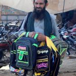 A street vendor selling school bags while shuttling on Khanewal Road