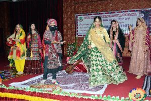 Female students performing tableau on stage at Shah Latif Girls College
