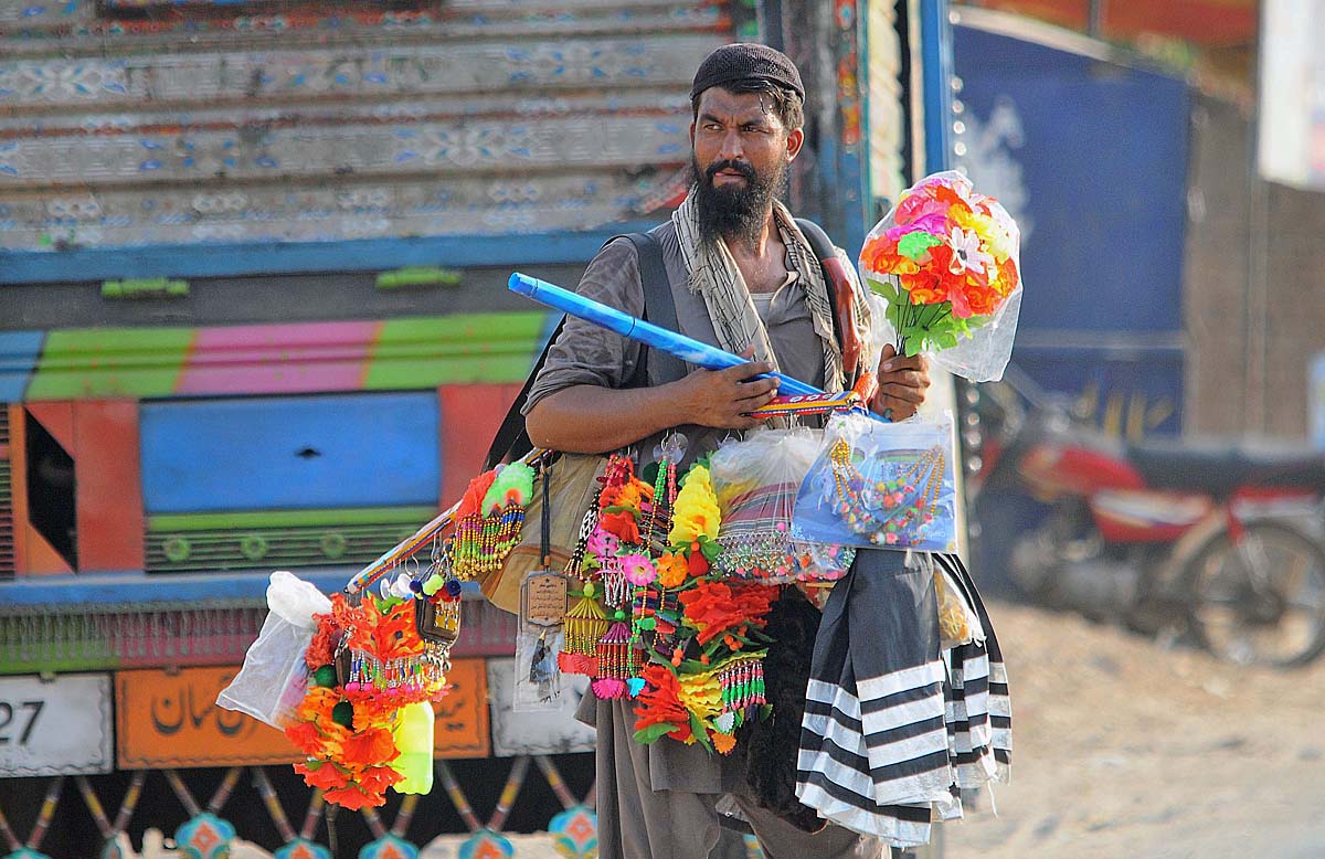 A vendor displaying decorative stuff for sale to attract customers while shuttling on Khanewal Road.